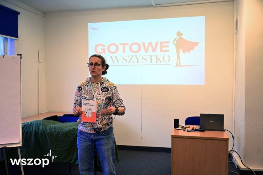 płk rez. dr Izabela Wlizło trzyma poradnik bezpieczeństwa na tle napisu Gotowe na wszystko