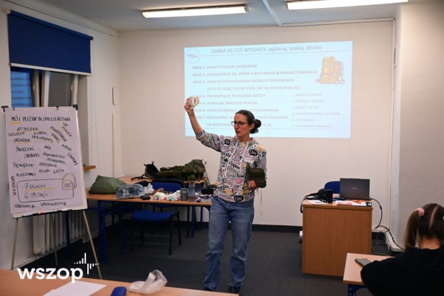 Płk rez. dr Izabela Wlizło pokazuje wyposażenie na tle slajdu o planowaniu ewakuacji.